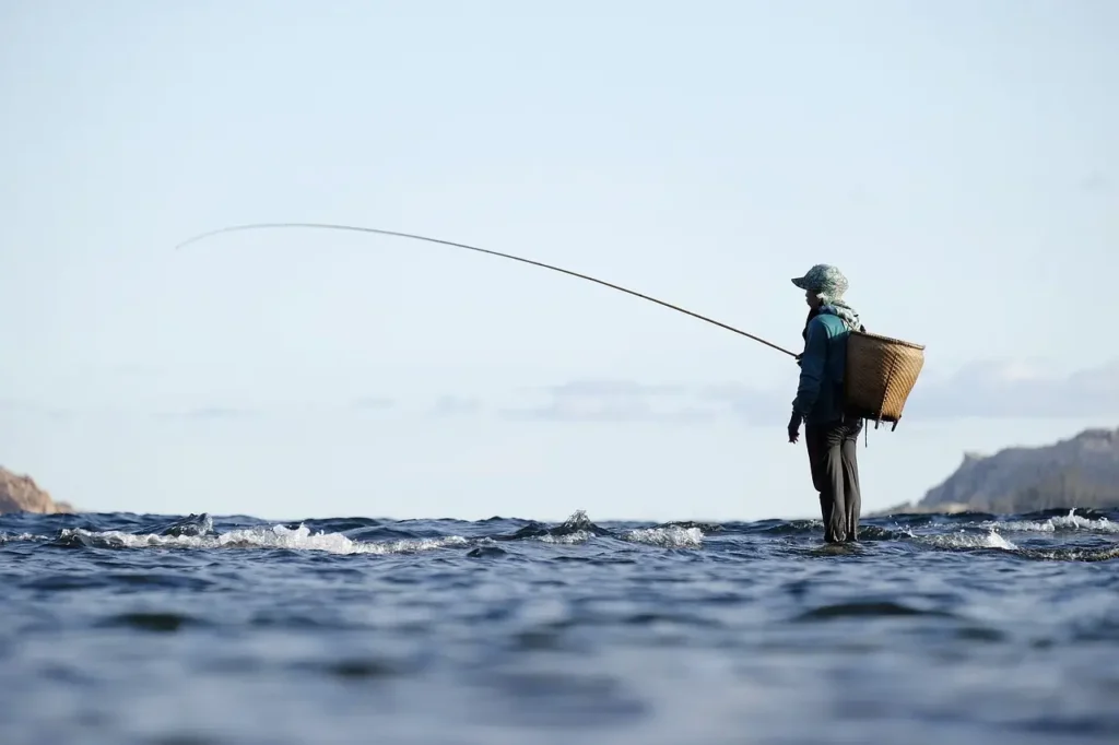 mulher na praia usando vara de pesca